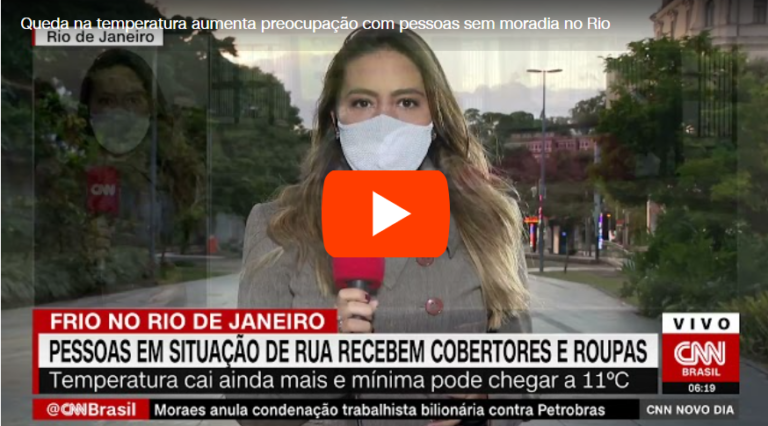 Jornalista Mylena Guedes CNN no Rio está de máscara branca e segura um microfone vermelho enquanto apresenta a matéria
